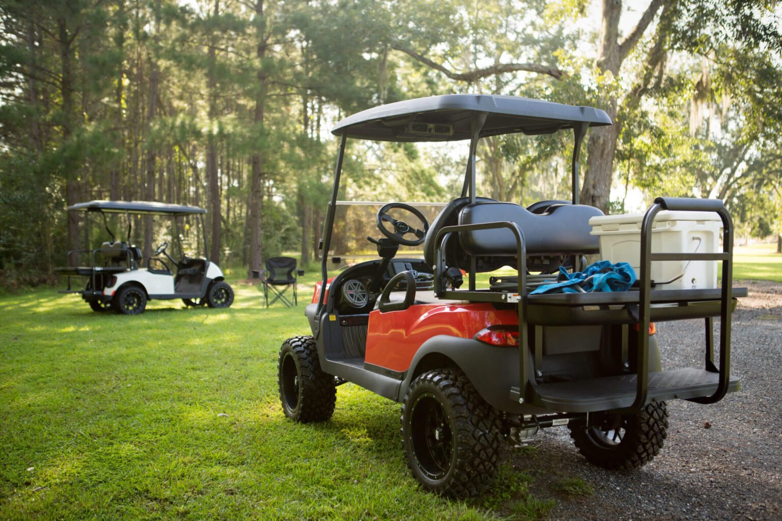Two colorful golf carts parked on grass next to a golf course
